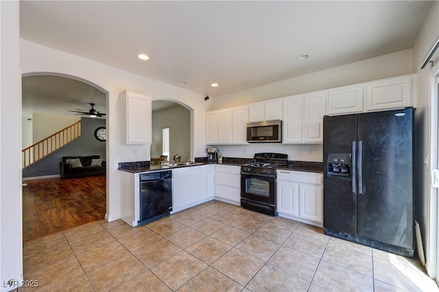 8169 Skytop Ledge Ave, Las Vegas, NV 89178 - kitchen with black appliances, dark countertops, arched walkways, light tile patterned floors, and white cabinets