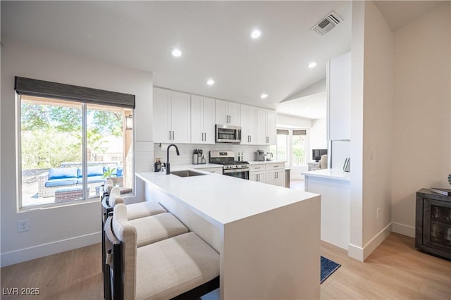 2548 Tumble Brook Dr, Las Vegas, NV 89134 - kitchen featuring appliances with stainless steel finishes, white cabinets, light wood finished floors, a peninsula, and light countertops