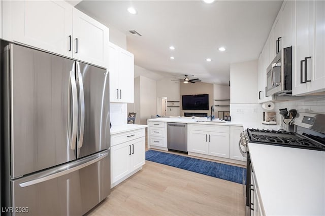 2548 Tumble Brook Dr, Las Vegas, NV 89134 - kitchen featuring stainless steel appliances, tasteful backsplash, white cabinets, light wood-type flooring, and a ceiling fan