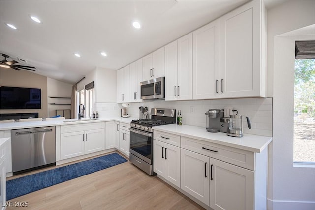2548 Tumble Brook Dr, Las Vegas, NV 89134 - kitchen featuring appliances with stainless steel finishes, backsplash, light wood-type flooring, white cabinetry, and open floor plan