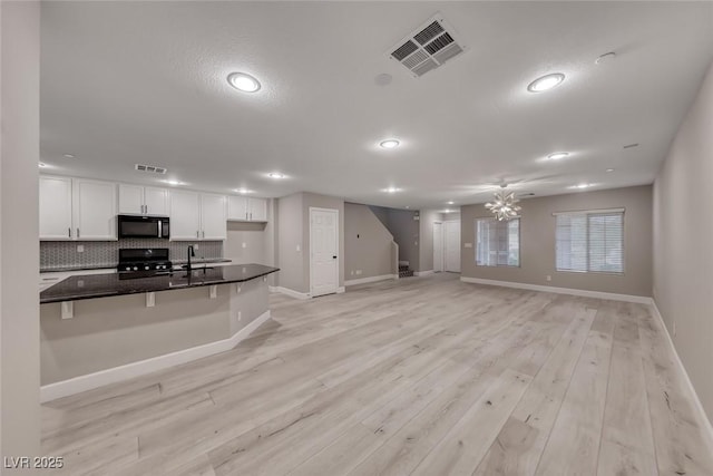 2337 Via Barranca St, Henderson, NV 89044 - kitchen featuring white cabinetry, black appliances, decorative backsplash, open floor plan, and a kitchen bar