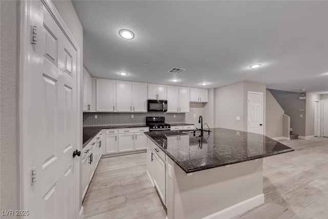 2337 Via Barranca St, Henderson, NV 89044 - kitchen with stainless steel range with gas cooktop, white cabinets, black microwave, dark stone counters, and recessed lighting