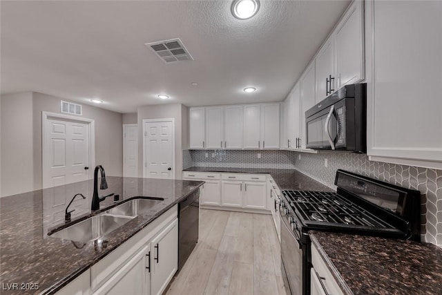 2337 Via Barranca St, Henderson, NV 89044 - kitchen featuring black appliances, white cabinetry, dark stone countertops, light wood-style floors, and tasteful backsplash