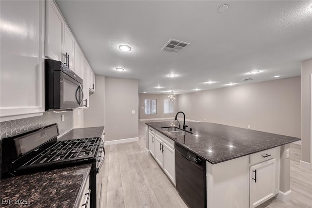 2337 Via Barranca St, Henderson, NV 89044 - kitchen featuring black appliances, light wood-style floors, white cabinetry, dark stone countertops, and a center island with sink
