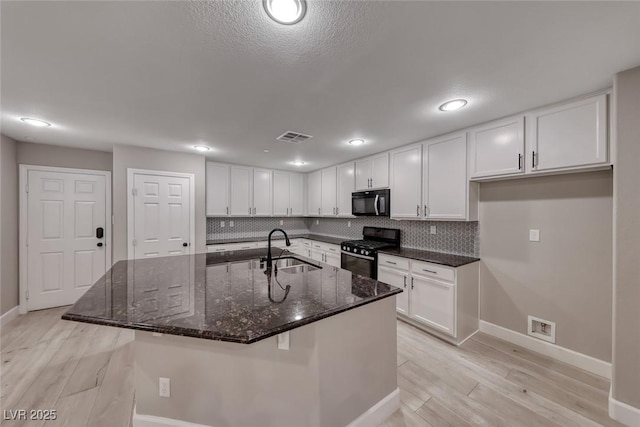 2337 Via Barranca St, Henderson, NV 89044 - kitchen with white cabinets, black appliances, light wood finished floors, tasteful backsplash, and recessed lighting