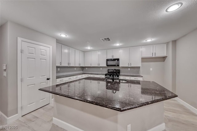 2337 Via Barranca St, Henderson, NV 89044 - kitchen with white cabinetry, decorative backsplash, black appliances, and recessed lighting
