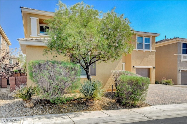 4208 Falcons Flight Ave, North Las Vegas, NV 89084 - view of property hidden behind natural elements featuring stucco siding, an attached garage, and decorative driveway