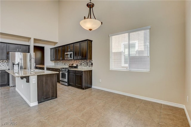 4208 Falcons Flight Ave, North Las Vegas, NV 89084 - kitchen featuring stainless steel appliances, tasteful backsplash, a towering ceiling, light tile patterned floors, and light stone countertops
