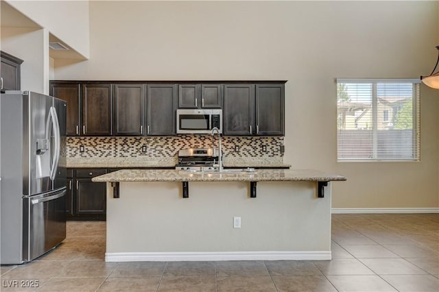 4208 Falcons Flight Ave, North Las Vegas, NV 89084 - kitchen featuring stainless steel appliances, decorative backsplash, light tile patterned floors, and a high ceiling