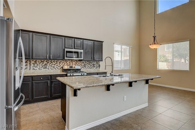 4208 Falcons Flight Ave, North Las Vegas, NV 89084 - kitchen featuring appliances with stainless steel finishes, a high ceiling, light tile patterned flooring, tasteful backsplash, and a breakfast bar area