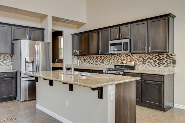 4208 Falcons Flight Ave, North Las Vegas, NV 89084 - kitchen with stainless steel appliances, light tile patterned flooring, dark brown cabinetry, and a breakfast bar area
