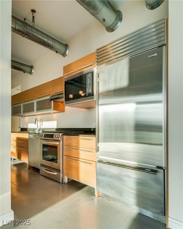 200 Hoover Ave Unit 903, Las Vegas, NV 89101 - kitchen with built in appliances, under cabinet range hood, dark countertops, and brown cabinetry