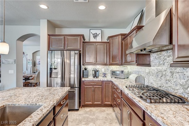 3605 Greenbriar Bluff Ave, North Las Vegas, NV 89081 - kitchen featuring wall chimney range hood, appliances with stainless steel finishes, arched walkways, light stone counters, and recessed lighting
