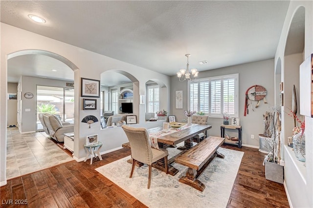 3605 Greenbriar Bluff Ave, North Las Vegas, NV 89081 - dining area featuring arched walkways, dark wood finished floors, and a chandelier
