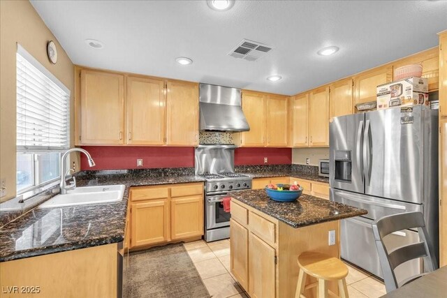 9836 La Vid Ct, Las Vegas, NV 89117 - kitchen with appliances with stainless steel finishes, wall chimney range hood, light brown cabinetry, dark stone counters, and recessed lighting