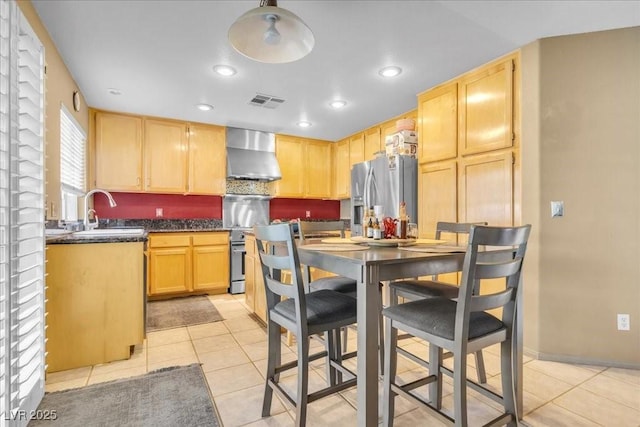 9836 La Vid Ct, Las Vegas, NV 89117 - kitchen featuring stainless steel appliances, wall chimney range hood, light brown cabinetry, dark countertops, and light tile patterned floors