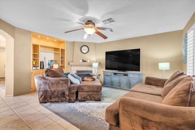 9836 La Vid Ct, Las Vegas, NV 89117 - living room with ceiling fan, arched walkways, light tile patterned floors, a fireplace, and built in shelves