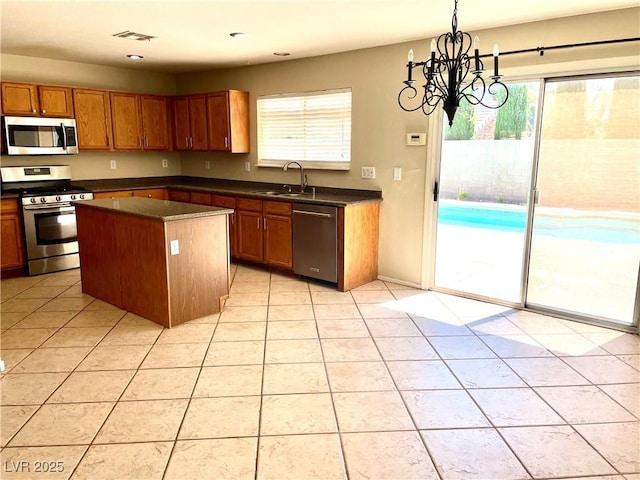 164 Swale Ln, Las Vegas, NV 89144 - kitchen with appliances with stainless steel finishes, dark countertops, light tile patterned floors, a center island, and a chandelier