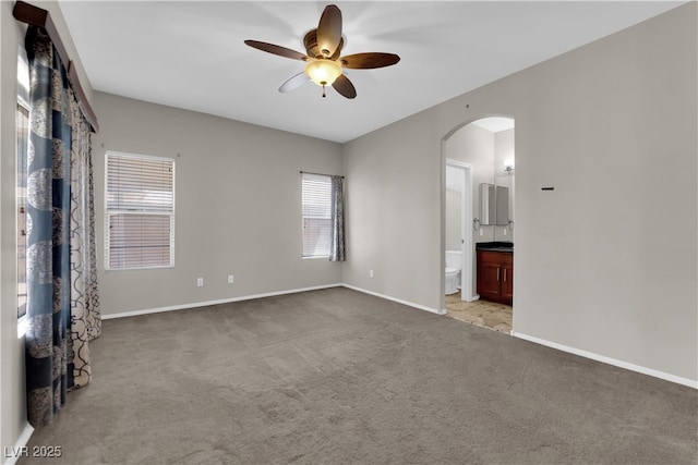 1205 Boulder Shore Ave, North Las Vegas, NV 89081 - unfurnished bedroom featuring arched walkways, carpet flooring, ensuite bathroom, and a ceiling fan