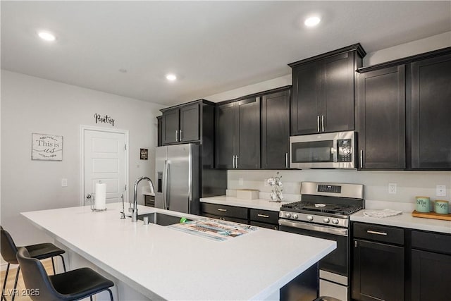 7009 Judith River St, North Las Vegas, NV 89084 - kitchen featuring appliances with stainless steel finishes, an island with sink, a breakfast bar, light countertops, and dark cabinets