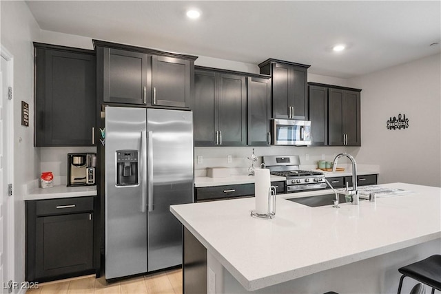 7009 Judith River St, North Las Vegas, NV 89084 - kitchen with stainless steel appliances, light countertops, a center island with sink, a kitchen bar, and dark cabinetry