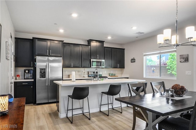 7009 Judith River St, North Las Vegas, NV 89084 - kitchen featuring stainless steel appliances, a kitchen island with sink, light countertops, a chandelier, and dark cabinetry