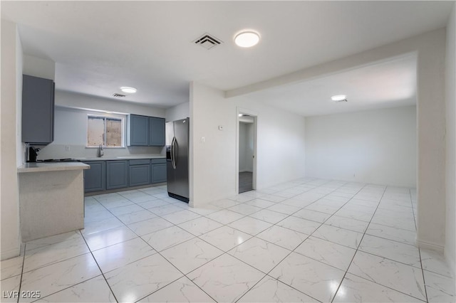 5317 Lytton Ave, Las Vegas, NV 89146 - kitchen featuring stainless steel fridge with ice dispenser, light countertops, light marble finish floors, and blue cabinets