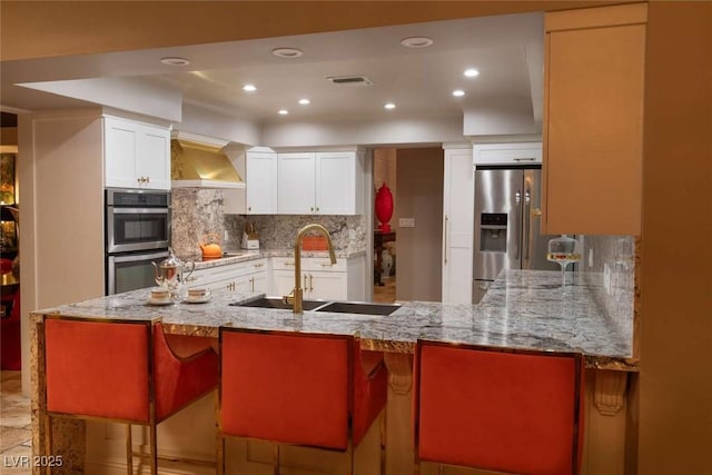 2030 Mohigan Way, Las Vegas, NV 89169 - kitchen featuring appliances with stainless steel finishes, custom exhaust hood, backsplash, a peninsula, and recessed lighting