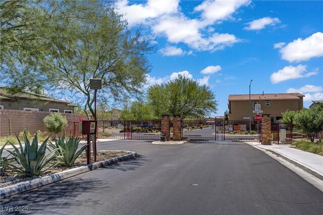 7546 Cooks Meadow St, North Las Vegas, NV 89084 - view of asphalt road with a gate, a gated entry, and street lights