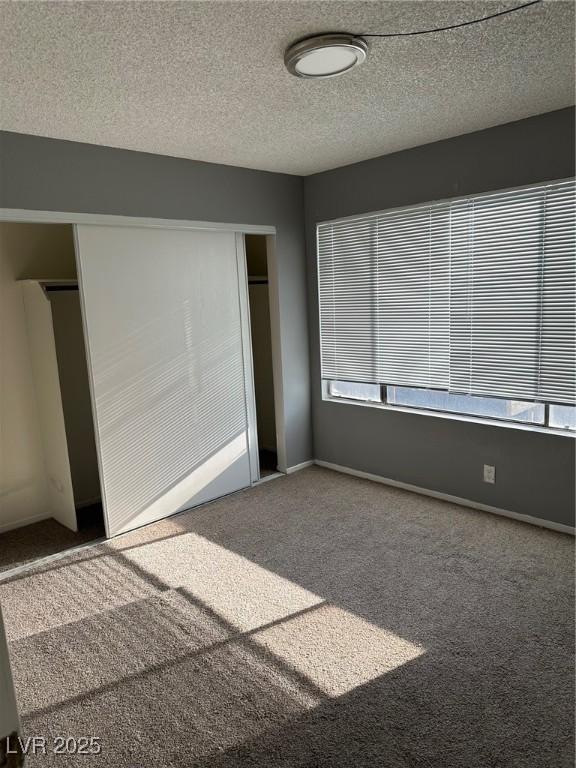 4241 Gannet Cir Unit 202, Las Vegas, NV 89103 - unfurnished bedroom featuring carpet flooring, a closet, multiple windows, and a textured ceiling