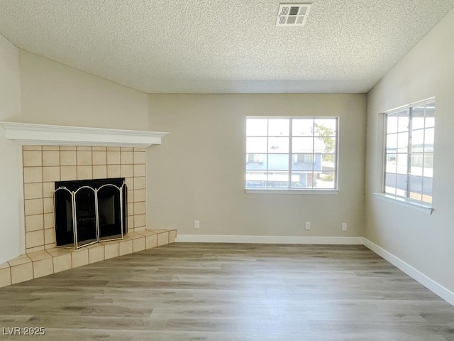 5385 Shake Ct Unit 203, Las Vegas, NV 89122 - unfurnished living room featuring wood finished floors, a textured ceiling, and a tiled fireplace