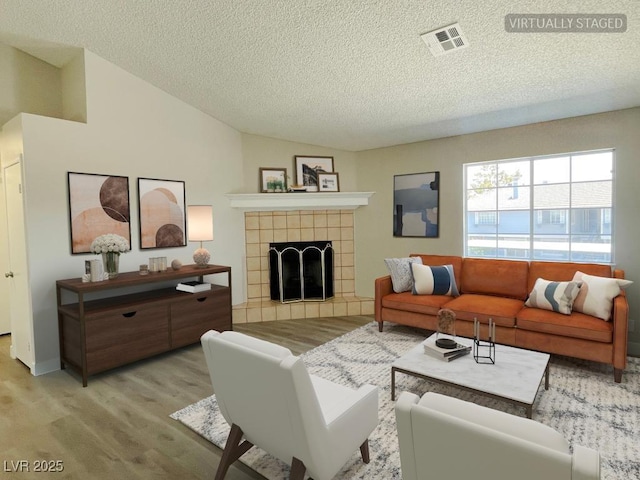 5385 Shake Ct Unit 203, Las Vegas, NV 89122 - living room with a textured ceiling, lofted ceiling, light wood-type flooring, and a fireplace