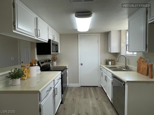 5385 Shake Ct Unit 203, Las Vegas, NV 89122 - kitchen featuring appliances with stainless steel finishes, light wood-type flooring, light countertops, and white cabinets
