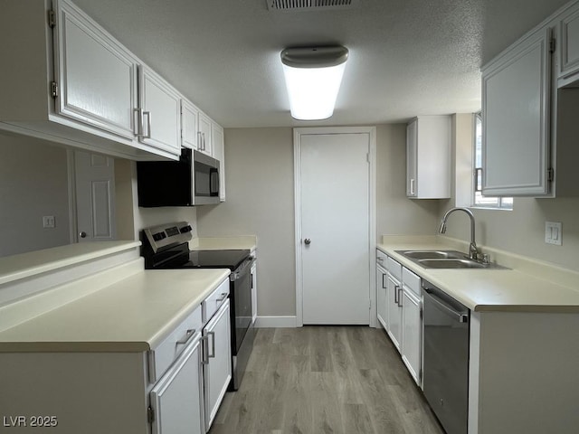 5385 Shake Ct Unit 203, Las Vegas, NV 89122 - kitchen with appliances with stainless steel finishes, light wood finished floors, light countertops, white cabinetry, and a textured ceiling