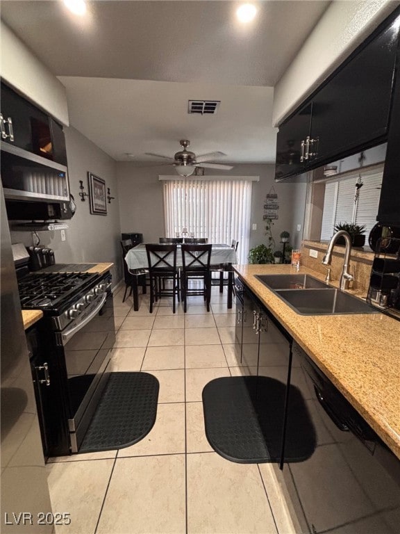 1600 N Torrey Pines Dr Unit 101, Las Vegas, NV 89108 - kitchen with stainless steel gas range, light tile patterned floors, light countertops, dark cabinets, and a ceiling fan