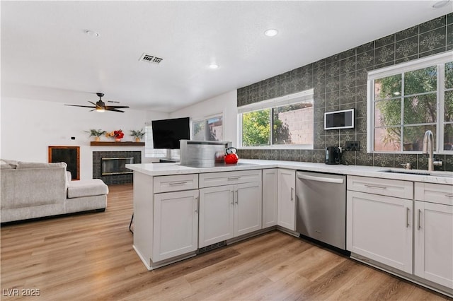 4305 Threshold Ct, North Las Vegas, NV 89032 - kitchen featuring dishwasher, a ceiling fan, a peninsula, backsplash, and a glass covered fireplace