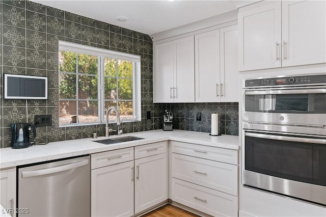 4305 Threshold Ct, North Las Vegas, NV 89032 - kitchen with stainless steel appliances, backsplash, light stone counters, and white cabinetry