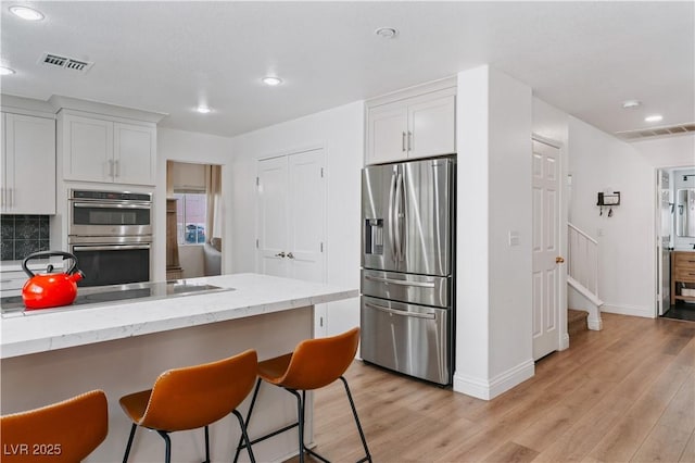 4305 Threshold Ct, North Las Vegas, NV 89032 - kitchen featuring appliances with stainless steel finishes, light wood-style floors, recessed lighting, white cabinetry, and a breakfast bar area