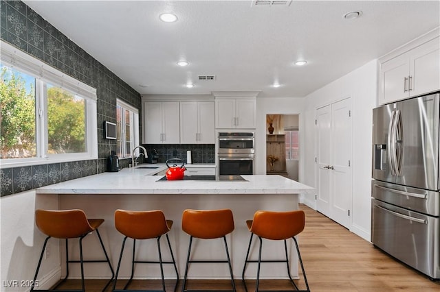 4305 Threshold Ct, North Las Vegas, NV 89032 - kitchen featuring appliances with stainless steel finishes, a peninsula, white cabinets, light wood-type flooring, and recessed lighting