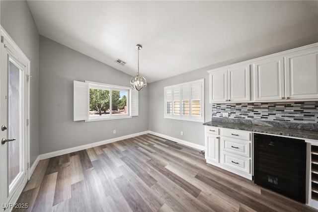5210 E Chasemoor St, Pahrump, NV 89061 - bar area featuring a chandelier, vaulted ceiling, backsplash, wood finished floors, and decorative light fixtures