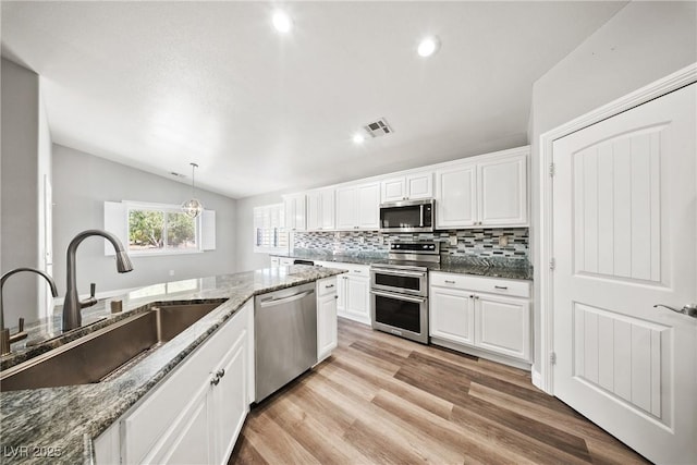5210 E Chasemoor St, Pahrump, NV 89061 - kitchen with stainless steel appliances, lofted ceiling, backsplash, white cabinets, and light wood-type flooring