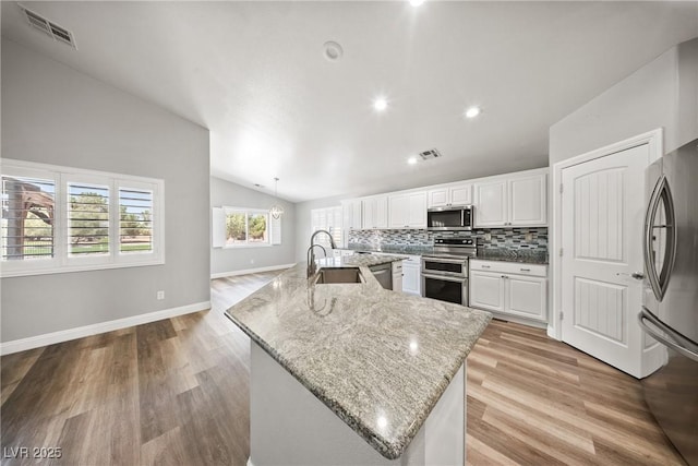 5210 E Chasemoor St, Pahrump, NV 89061 - kitchen with appliances with stainless steel finishes, vaulted ceiling, a large island, light wood-style flooring, and decorative backsplash