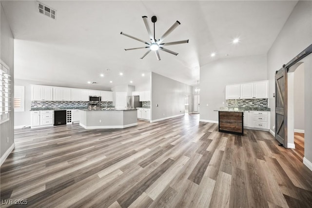 5210 E Chasemoor St, Pahrump, NV 89061 - unfurnished living room with a barn door, ceiling fan, recessed lighting, light wood-style floors, and beverage cooler