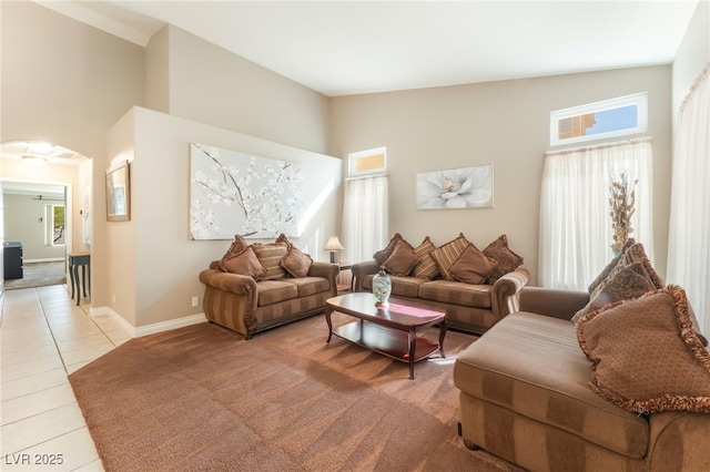 1442 Big Tree Ave, North Las Vegas, NV 89031 - living room with light tile patterned floors, a towering ceiling, arched walkways, and light carpet