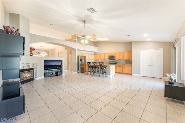 1442 Big Tree Ave, North Las Vegas, NV 89031 - living room with vaulted ceiling, light tile patterned floors, ceiling fan, a tiled fireplace, and arched walkways