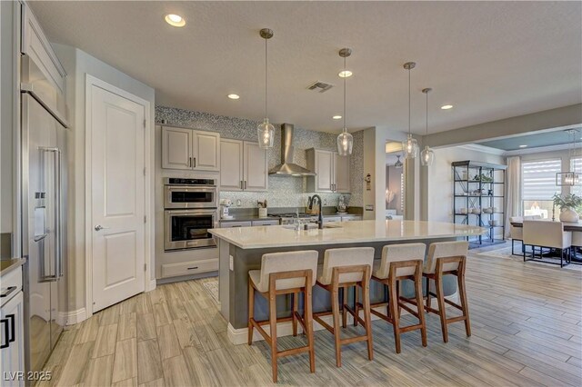 9964 Peaceful Peaks Ave, Las Vegas, NV 89166 - kitchen featuring wall chimney exhaust hood, double oven, backsplash, light wood-type flooring, and recessed lighting