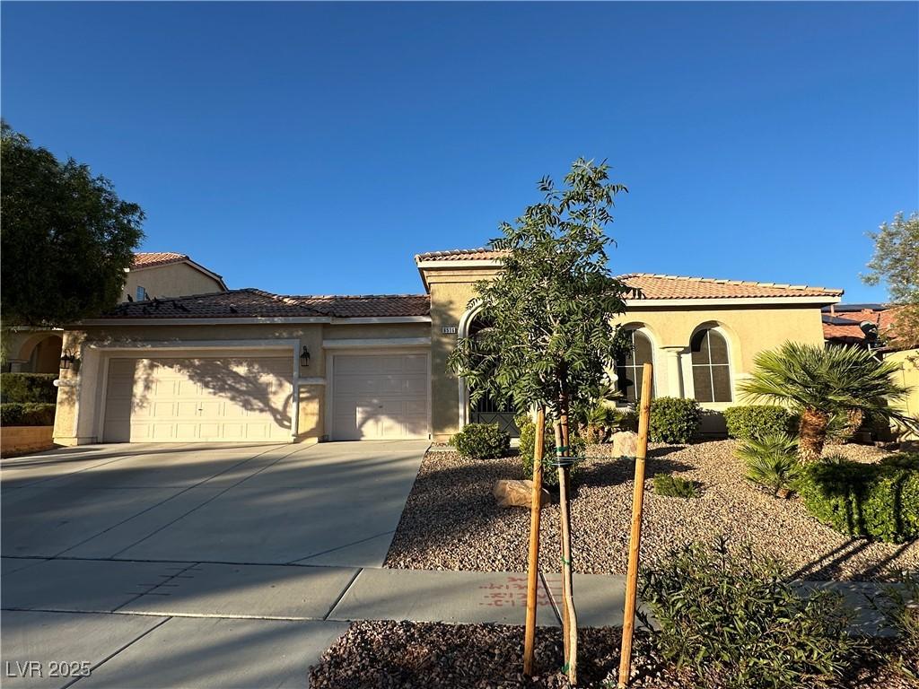 6536 Black Oaks St, North Las Vegas, NV 89084 - mediterranean / spanish house featuring stucco siding, a garage, concrete driveway, and a tiled roof