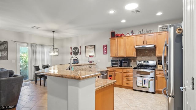 7723 Widewing Dr, North Las Vegas, NV 89084 - kitchen featuring appliances with stainless steel finishes, under cabinet range hood, light tile patterned flooring, tasteful backsplash, and an island with sink