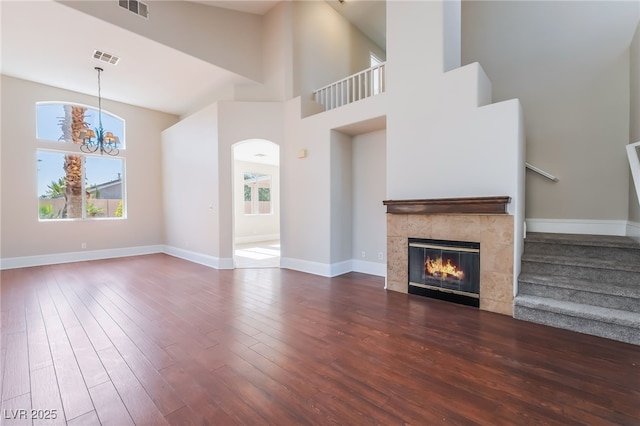 258 Horizon Pointe Cir, Henderson, NV 89012 - unfurnished living room with stairs, a chandelier, wood finished floors, a fireplace, and a towering ceiling