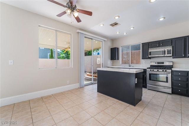 258 Horizon Pointe Cir, Henderson, NV 89012 - kitchen featuring appliances with stainless steel finishes, tile counters, dark cabinetry, a ceiling fan, and a kitchen island